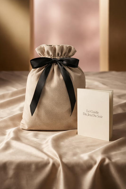 pochette de rangement le jeu du soir avec son guide de jeu romantique pas-à-pas  pour couple posé sur des draps satinés 